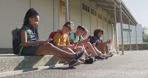 Diverse Kids at School Engaging with Smartphones Outdoors