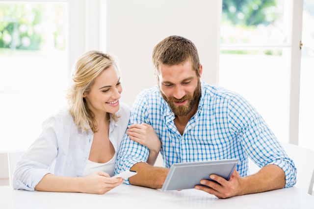 Smiling couple using digital tablet at home
