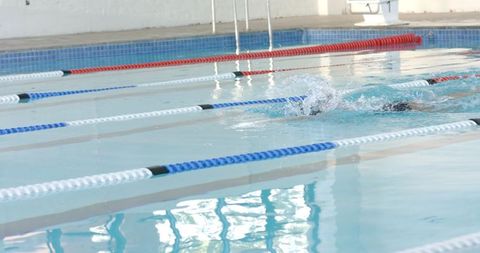 Swimmer gliding through indoor pool lanes focused on competition