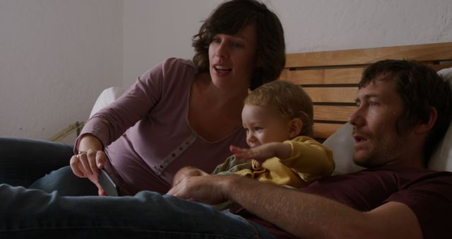 Young Family Watching TV on Bed During Relaxing Evening - Download Free Stock Images Pikwizard.com