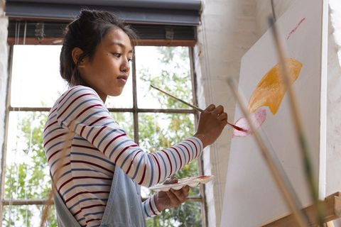 Creative young woman painting abstract art in bright studio