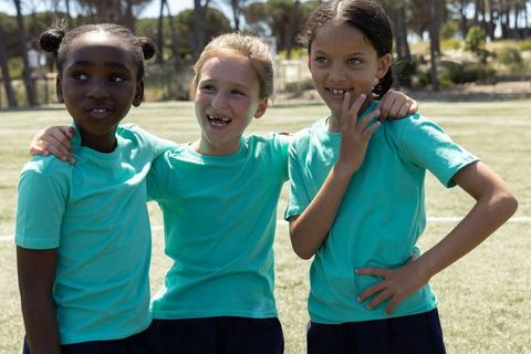 Youth team friendship on soccer field wearing matching teal shirts and dark shorts