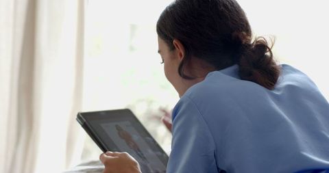 Nurse in blue scrubs using tablet indoors for medical records