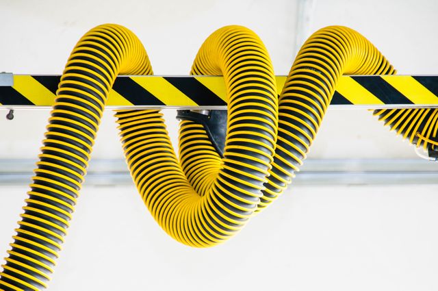 Yellow air hoses with black stripes seen in factory environment, highlighting industrial machinery and piping. Ideal visual for articles related to manufacturing, engineering, with applications in HVAC systems, workplace safety systems, and technical equipment.