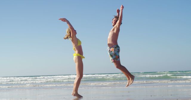 Happy Couple Jumping on Sunny Beach Vacation - Download Free Stock Images Pikwizard.com