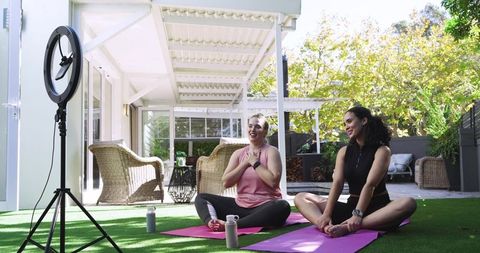 Diverse women practicing yoga outdoors with ring light setup