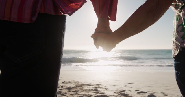 Caucasian senior couple holding hands walking on beach by seaside with copy space. Retirement, lifestyle, vacation, summer, happiness, wellbeing concept, unaltered.