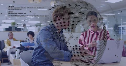 Colleagues collaborating over laptop with digital data overlay in modern coworking space