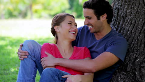 Young Couple Laughing Under Tree in Park