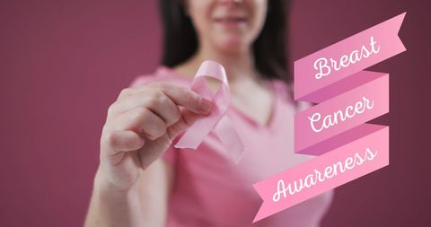Woman Holding Pink Ribbon for Breast Cancer Awareness on Pink Background