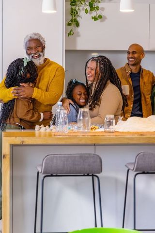 Multigenerational african american family laughing and hugging around kitchen island