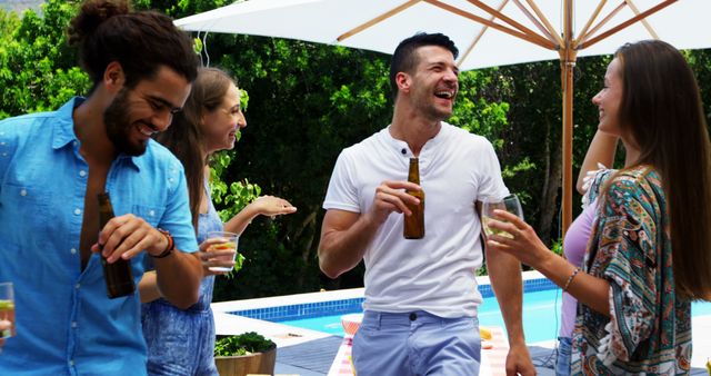 Group of friends enjoying a fun-filled gathering by the pool on a bright sunny day. They are holding drinks, laughing, and engaging in cheerful conversation. Ideal for promoting summer festivities, poolside events, alcoholic beverages, vacation packages, and social gatherings.