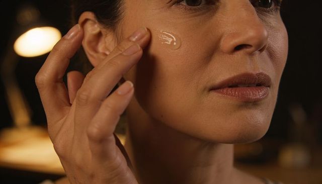 Applying facial serum with fingertips closeup, woman rubbing moisturizer on cheek