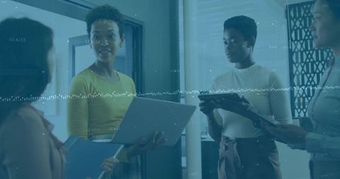Diverse women leading meeting with laptop and tablet, data visualization overlay