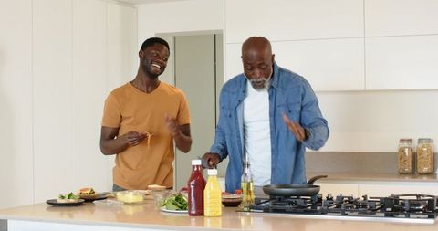 Father and Adult Son Cooking Together in Modern Kitchen