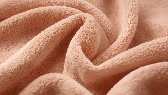 Peach plush fleece blanket showing deep folds and dense pile for cozy texture backgrounds