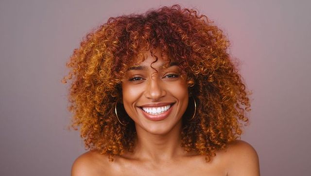 Smiling woman displaying curly hair and gold hoop earrings