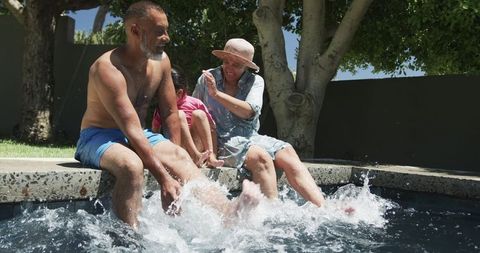 Grandfather, Granddaughter Enjoying Playful Poolside Fun Outdoors