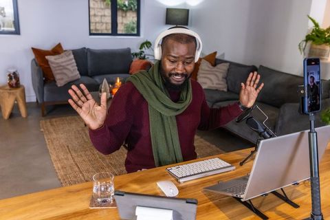 African american man hosting live video call wearing headphones in cozy modern home office