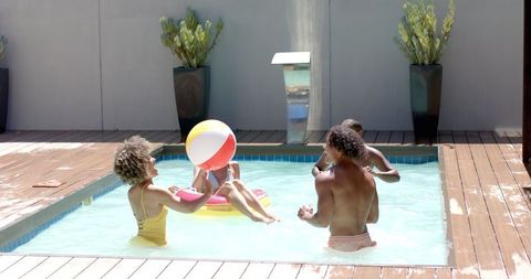 Diverse group enjoying energetic pool party with beach ball