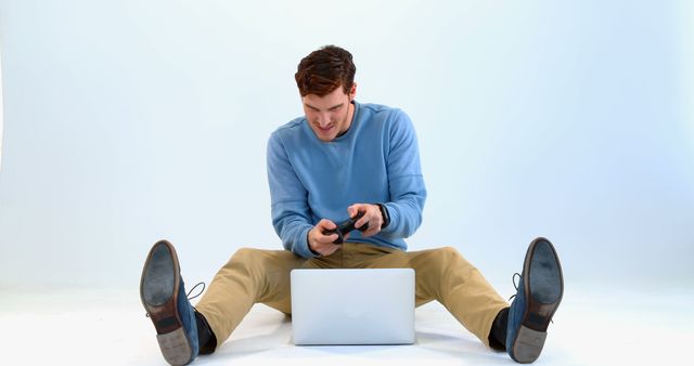 Young Man Smiling While Gaming with Laptop and Controller - Download Free Stock Images Pikwizard.com