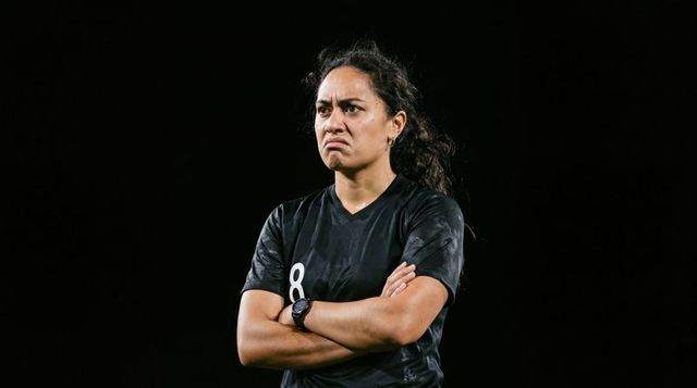 Intense female soccer player standing with arms crossed under stadium lights, jersey 8