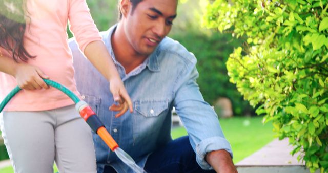 Father and Daughter Watering Plants with Hose in Garden - Download Free Stock Images Pikwizard.com