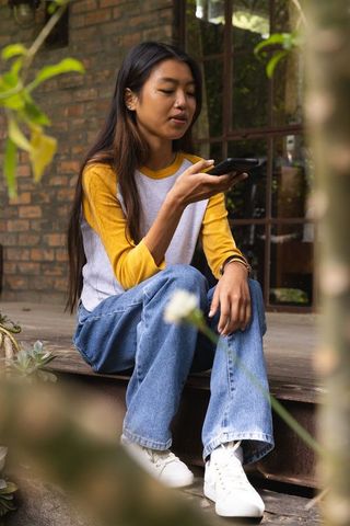 Woman Relaxing with Smartphone on Backyard Deck near Succulents