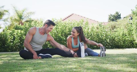 Active Couple Doing Yoga Stretches in Lush Garden