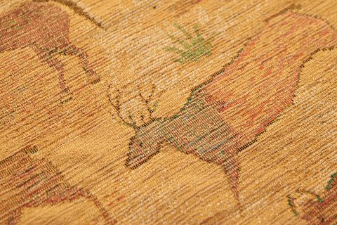 Handwoven wool rug featuring stylized deer motif, warm golden tones for rustic decor