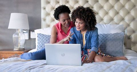 Mother and Daughter Enjoying Laptop Time Together on Bed