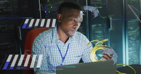 Technician inspecting yellow fiber cables while monitoring laptop with holographic overlays