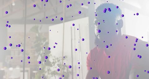 Man sitting behind glass divider with violet dot overlay in modern casual workspace portrait