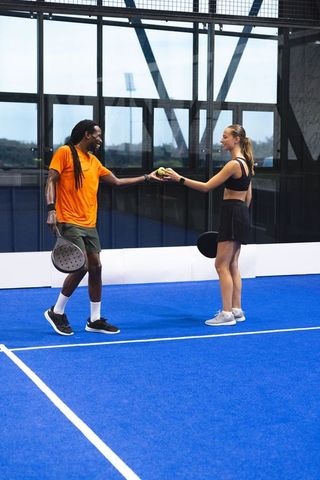 Friends Exercising on Modern Blue Padel Court With Rackets and Yellow Ball