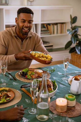 Joyful African American Man Serving Potatoes at Home Table Gathering