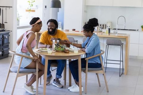 Family sharing meal at modern kitchen table laughing over casual breakfast