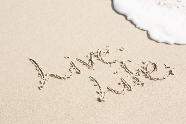 Handwritten message 'Live Life' on sandy beach with ocean waves approaching. Ideal for inspirational and motivational content, travel blogs, summer vacation promotions, and relaxation themes. Perfect for use in social media posts, website banners, and greeting cards.