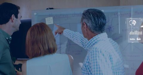 Senior leader pointing at whiteboard leading team brainstorming and strategy review