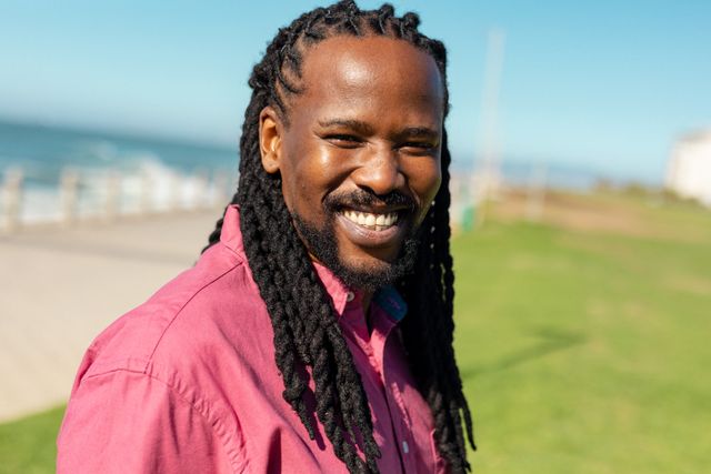 Portrait of smiling african american man with long braided black hair at promenade on sunny day. unaltered, lifestyle, hairstyle and summer concept.
