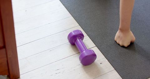 Arm workout at home with purple dumbbell and yoga mat