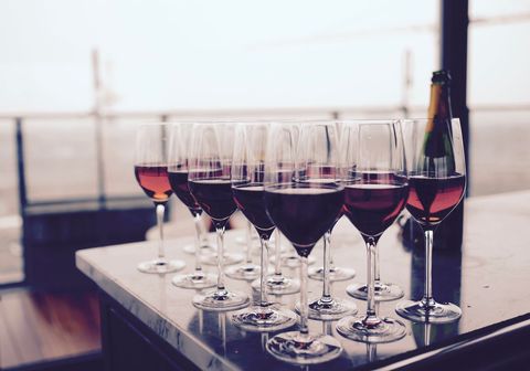 Row of Red Wine Glasses on Marble Counter with Champagne Bottle and Seaside View