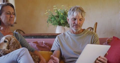 Senior Couple Using Tablet in Living Room with Pet Dog