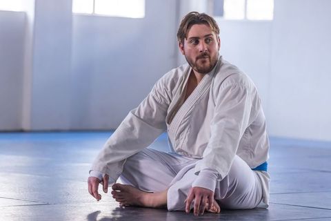 Asian Martial Artist Resting on Mat in Training Hall