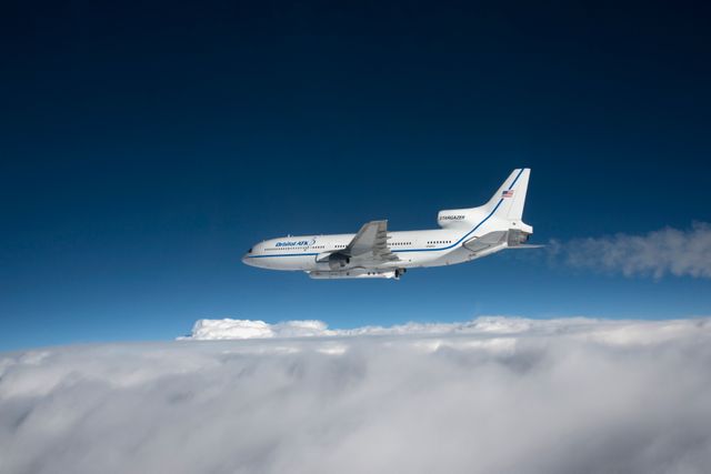 Orbital ATK L-1011 Stargazer aircraft flying over Atlantic Ocean near Daytona Beach, Florida on December 12, 2016. Pegasus XL rocket attached beneath aircraft containing eight CYGNSS spacecraft for studying ocean surface winds in tropical storms and hurricanes. Suitable for content about aerospace technology, satellite launches, or high-altitude aviation.