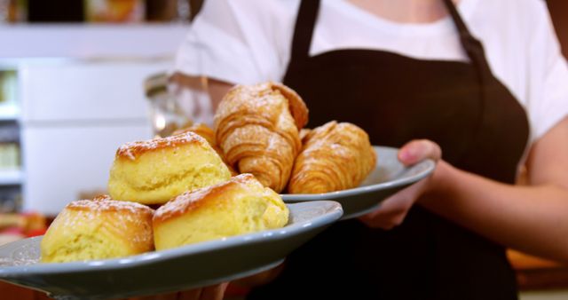 Waitress holding a plate of croissant and sweet food in cafe 4k