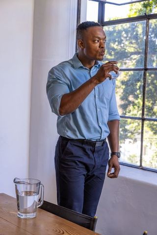 Professional Man Hydrating in Sunlit Office Setting