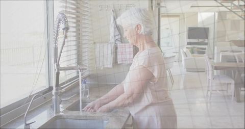 Senior Woman Washing Hands Under Modern Pull-Down Kitchen Faucet
