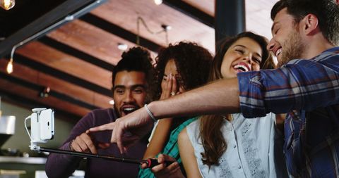 Group of Friends Using Selfie Stick in Modern Café