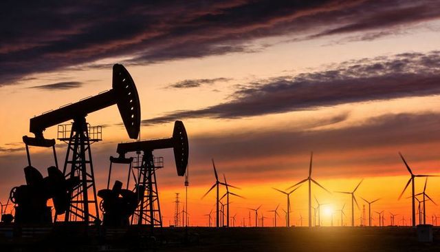 Sunset silhouettes of oil pumpjacks and wind turbines highlighting energy transition