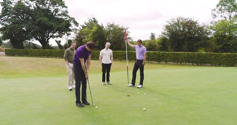 Friends Playing Golf on Lush Green Course Enthusiastic Game